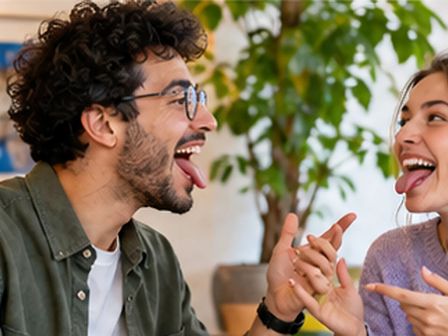 Two adults laughing during playful pronunciation practice in a bright indoor setting.